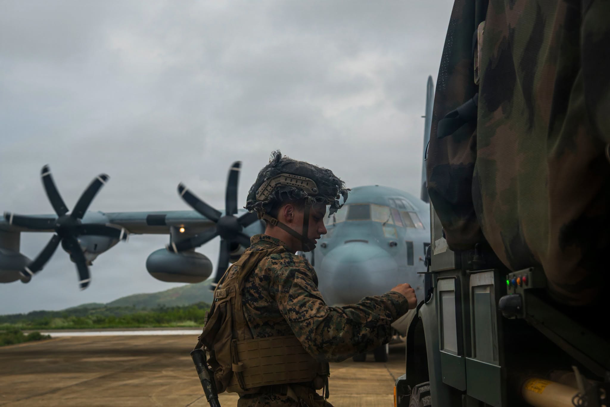 Marine Prepares Equipment Beside KC-130J Hercules